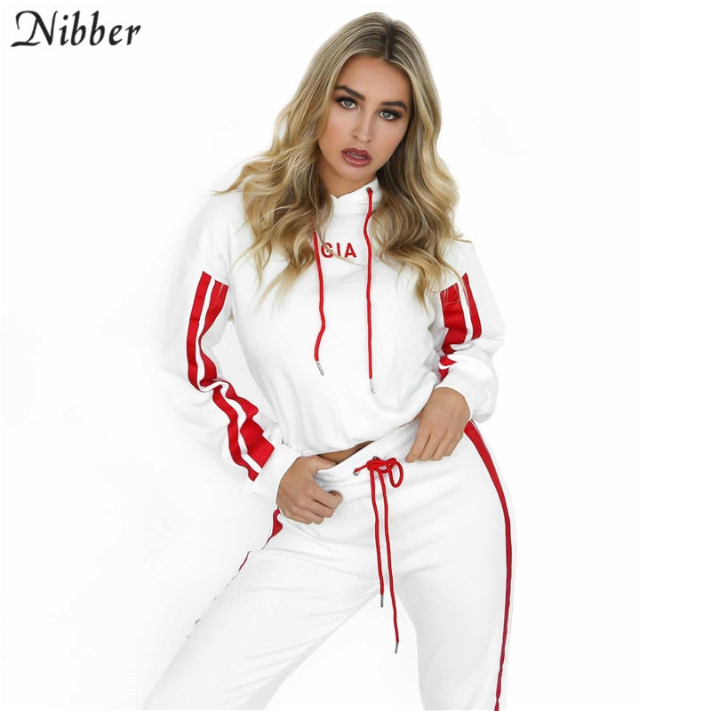Woman wearing a white tracksuit with red accents on a white background, featuring the brand 'Nibber'.